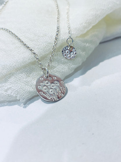 Silver necklace with a round pendant on a white fabric background