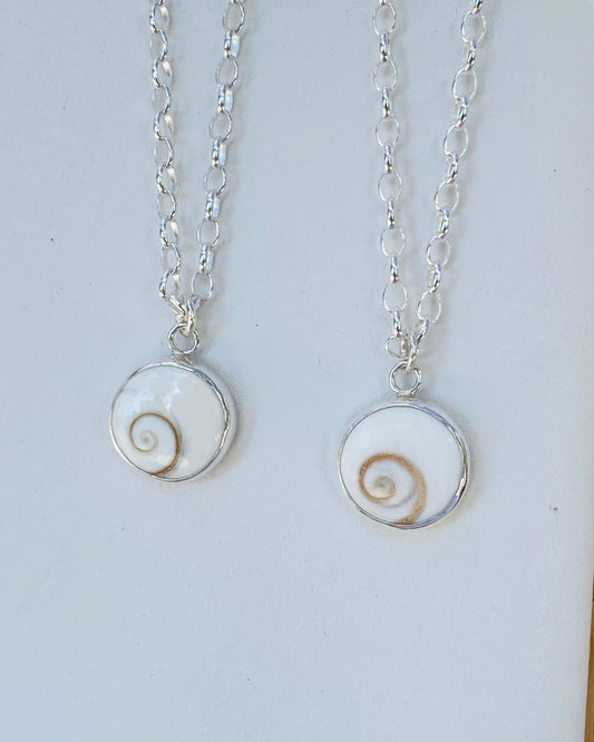 Two silver necklaces with circular pendants featuring round Shiva Eye spiral stones 